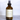 A 8 oz amber glass spray bottle of A'ola Lux Well Kept Interior Fragrance with a black spray nozzle and cream label, set against a grey marble background.
